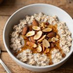 Bowl of Keto Maple Almond Oatmeal topped with toasted almonds and sugar-free maple syrup