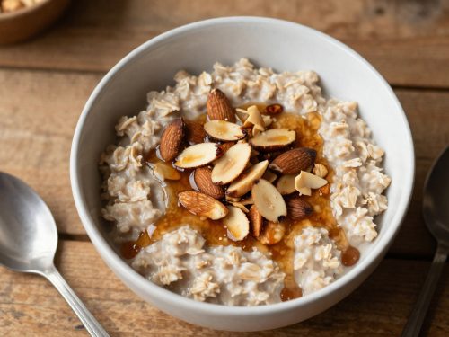 Bowl of Keto Maple Almond Oatmeal topped with toasted almonds and sugar-free maple syrup