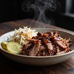 Keto BBQ pulled pork served in a bowl with sugar-free barbecue sauce, coleslaw, and pickles