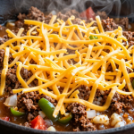 Shredded cheddar cheese layered over thick seasoned beef and vegetable mixture before melting for the One Pan Keto Taco Skillet